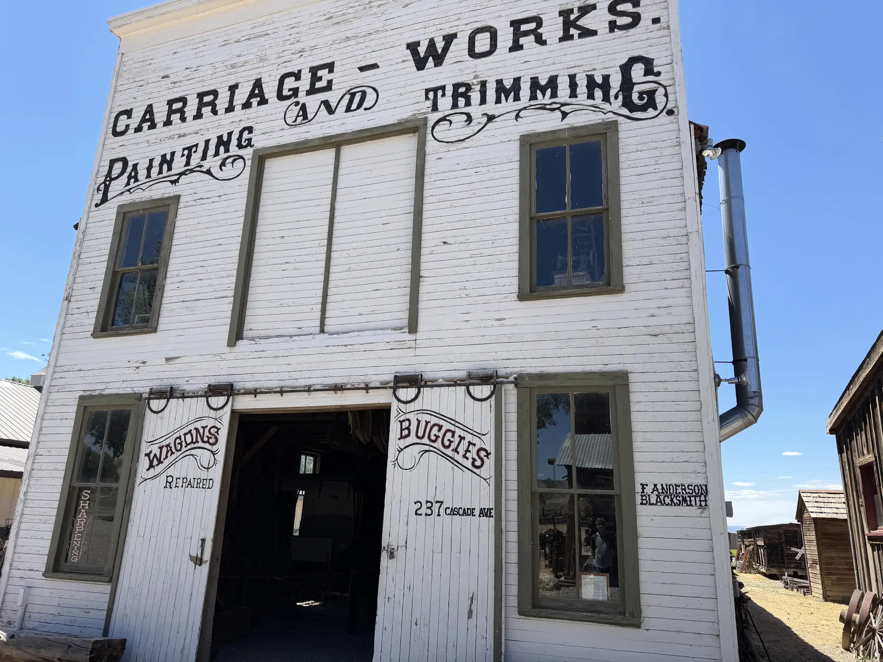 The painted white exterior of a historic carriage works building beneath a blue sky