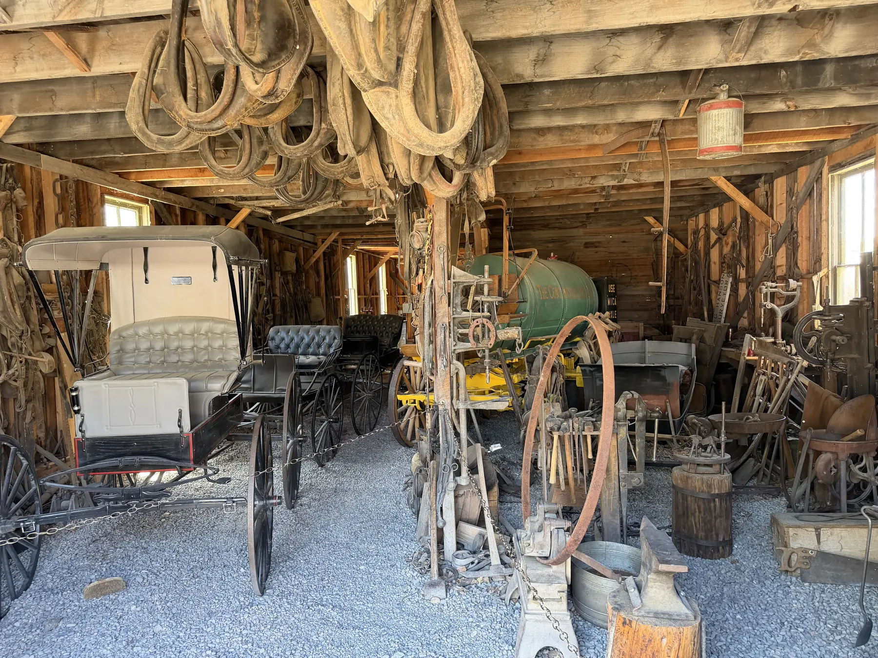 Horse-drawn carriages, wheels, ropes, and tools inside the historic carriage works